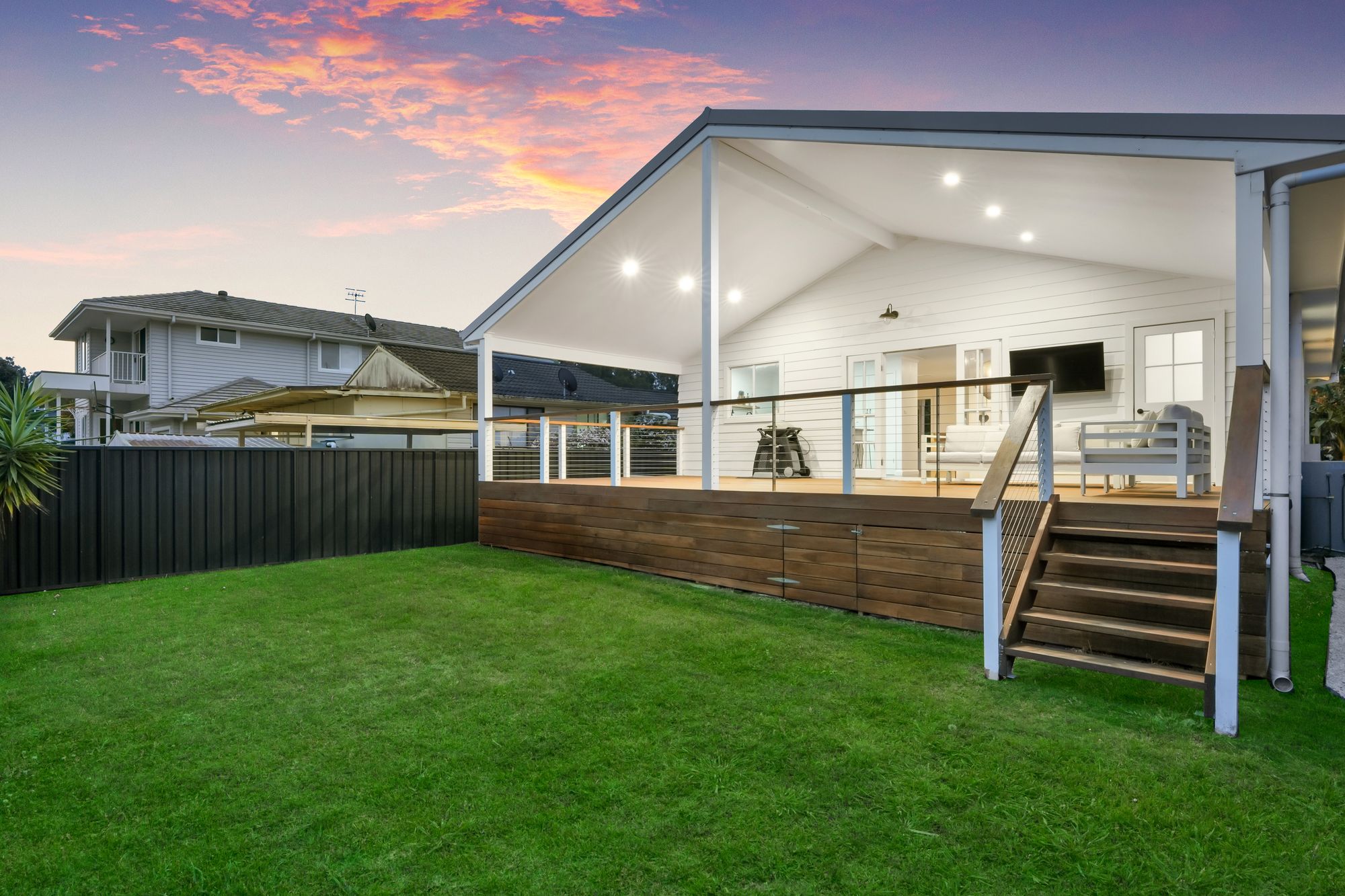 Covered hardwood deck with stairs to the lawn