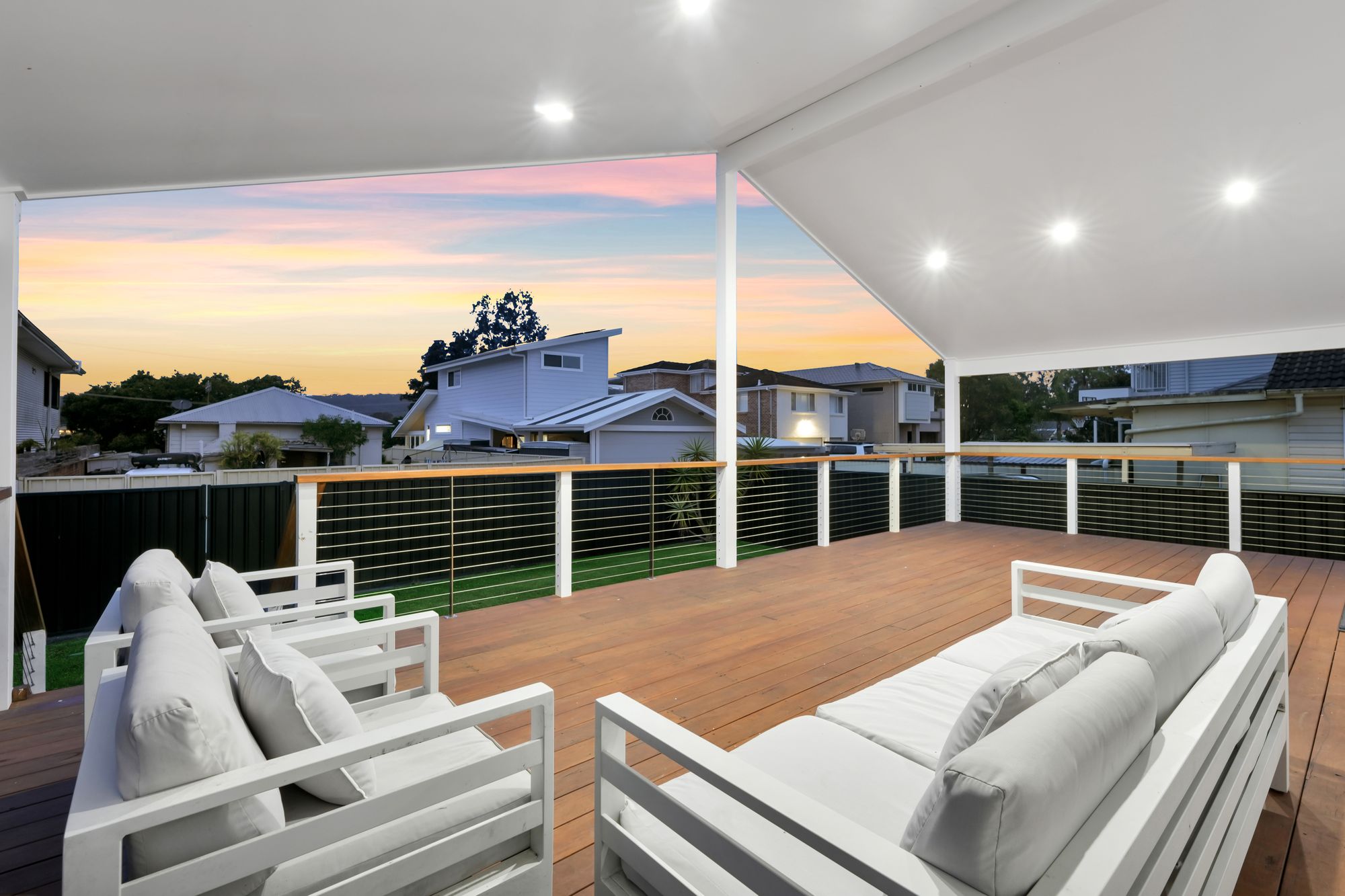 Covered deck with outdoor lounge at dusk by Scott JG Constructions